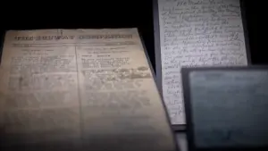 Seni istoriniai dokumentai ir rankraščiai, apšviesti prieblandoje, simbolizuojantys archyvines paieškas bei istorinę atmintį.