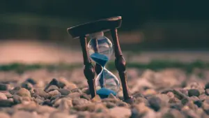Smėlio laikrodis ant akmenų simbolizuoja prabėgantį laiką ir gyvenimo prioritetus.
