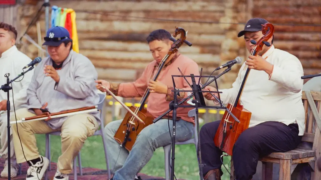 Muzikantai groja tradiciniais styginiais instrumentais lauke vykstančio renginio metu.
