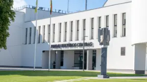 Šiuolaikinis administracinis pastatas su Lietuvos vėliava, reprezentuojantis valstybines įstaigas ir paslaugas.