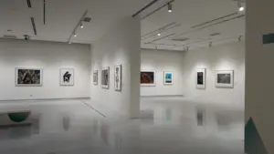 Šiuolaikinio meno galerijos erdvė su eksponuojamais meno kūriniais ant baltų sienų.