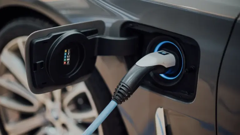 Elektromobilio įkrovimo laidas prijungtas prie automobilio įkrovimo lizdo viešoje stotelėje