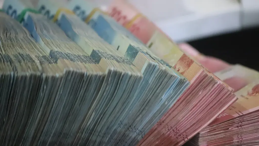 Didelės grynųjų pinigų krūvos, iliustruojančios finansinę sėkmę ir asmeninių finansų planavimą.
