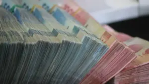 Didelės grynųjų pinigų krūvos, iliustruojančios finansinę sėkmę ir asmeninių finansų planavimą.