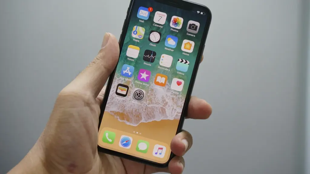 Rankoje laikomas naujausias „iPhone“ išmanusis telefonas su matoma programėlių skydeliu ekrane.