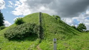 Istorinis piliakalnis su laiptais žaliuojančiame kraštovaizdyje atspindi Lietuvos istorinį palikimą.