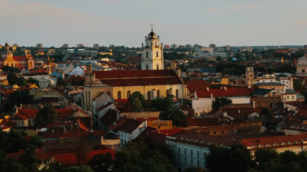 Panoraminis Vilniaus senamiesčio vaizdas su bažnyčios bokštais ir raudonais stogais.